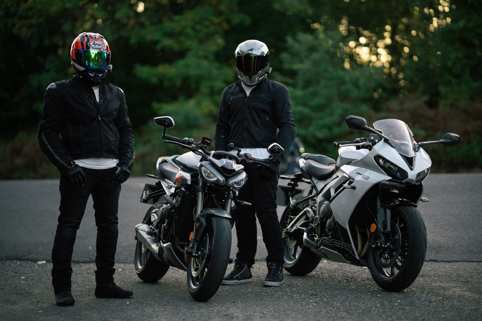 Two motorcyclists in gear, standing with their sport bikes on an open road